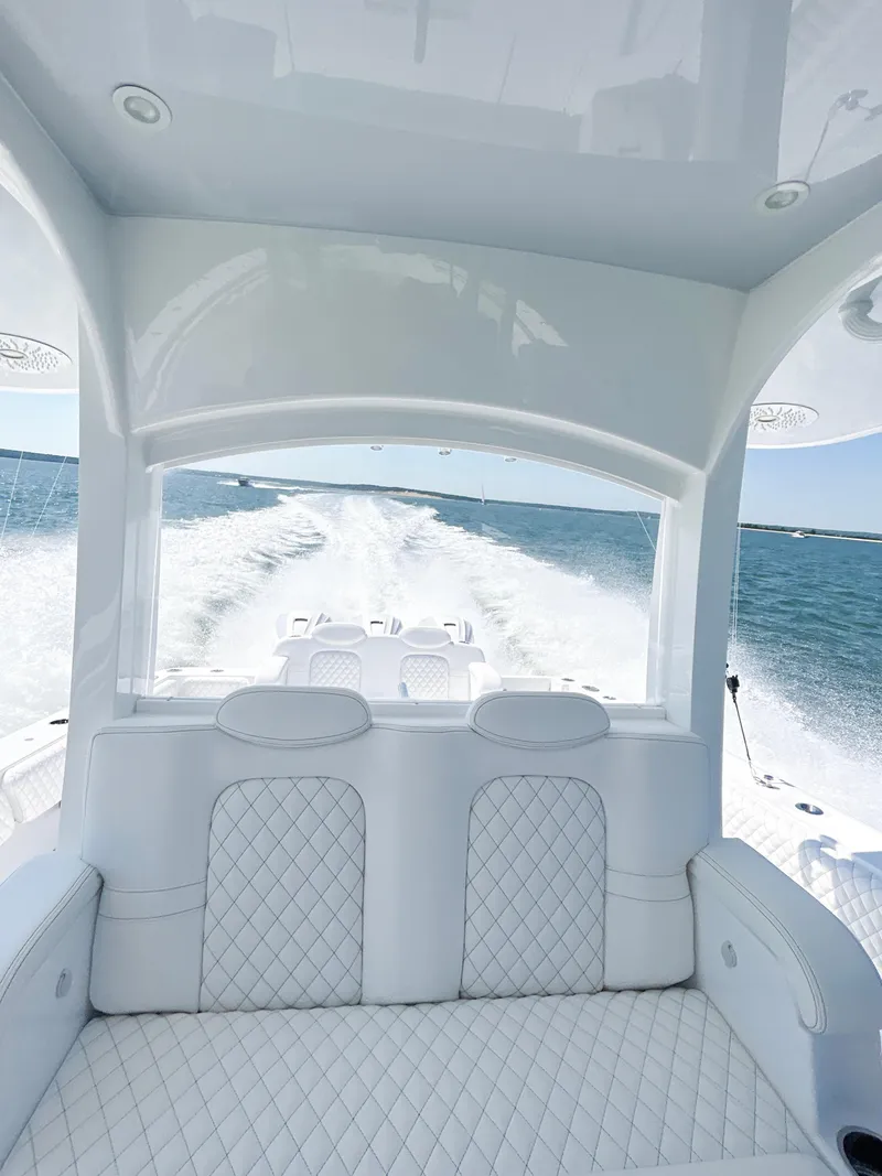Slide: The Image of 2024 HCB 42 Lujo luxury boat interior with white quilted seats on open water. - 15