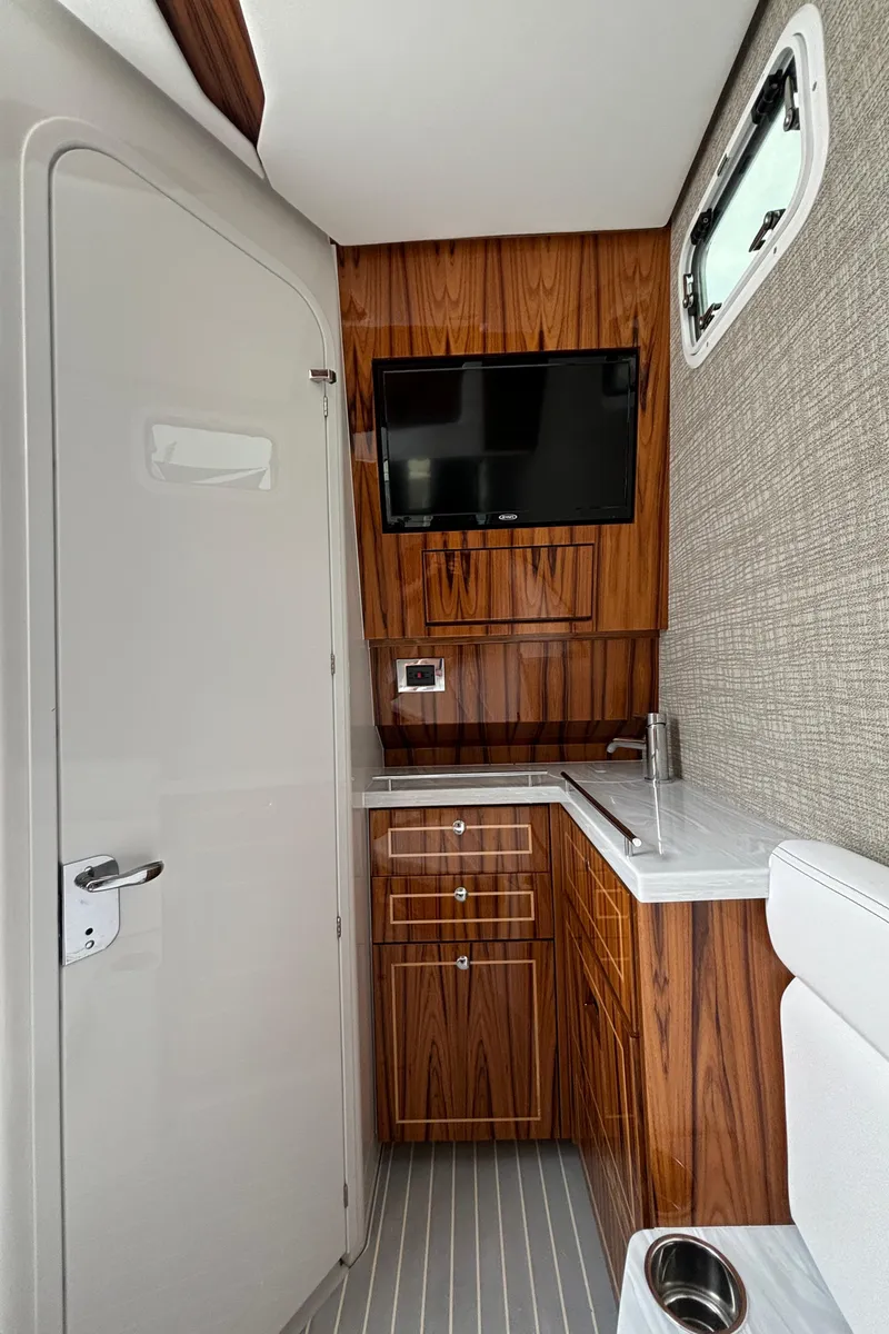 Slide: The Image of 2024 HCB 42 Lujo yacht interior with wood cabinetry, TV, and compact kitchenette. - 28