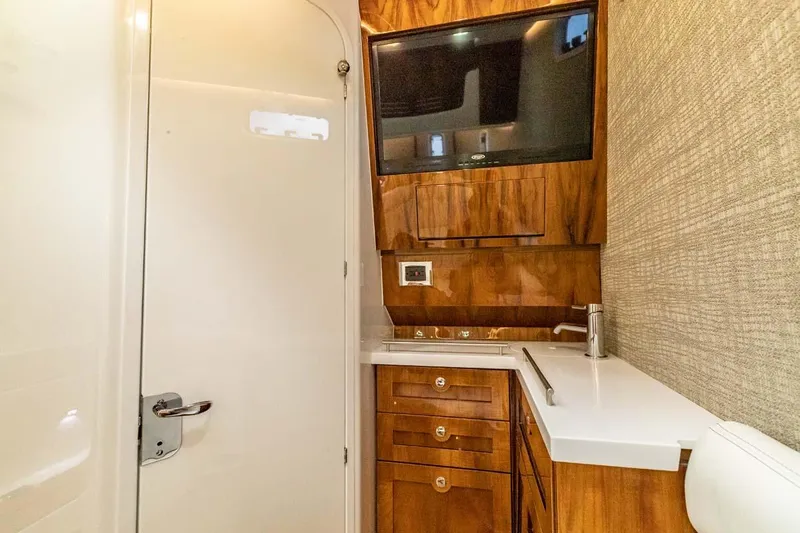 Slide: The Image of Luxurious bathroom in 2024 HCB 42 Lujo boat with TV, sink, and wooden cabinetry. - 7