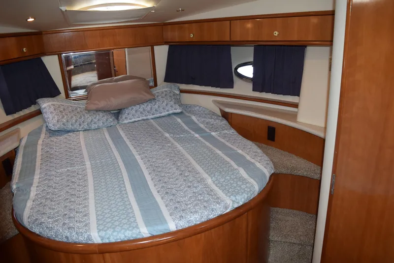 Slide: The Image of 2002 Carver 444 Cockpit Motoryacht bedroom with a large bed and wooden cabinetry. - 18