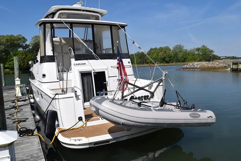 Slide: The Image of 2002 Carver 444 Cockpit Motoryacht docked with inflatable dinghy attached. - 2