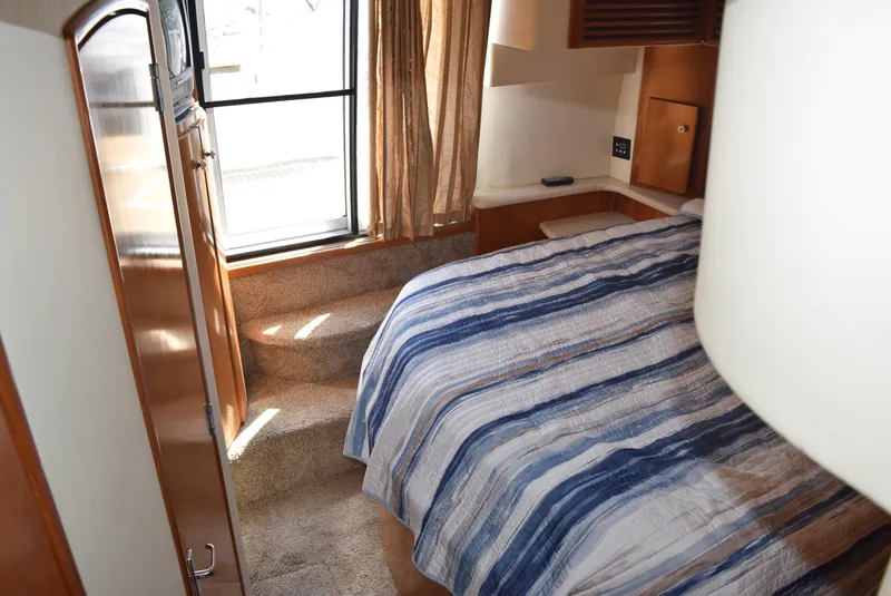 Slide: The Image of 2002 Carver 444 Cockpit Motoryacht bedroom with striped bedding and window view. - 21