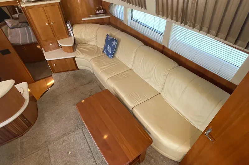 Slide: The Image of 2002 Carver 444 Cockpit Motoryacht interior with beige leather sofa and wooden table. - 33