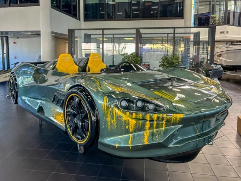 Slide: The Image of 2023 Watersports Car Series X in showroom, green with yellow accents, sleek design. - 1