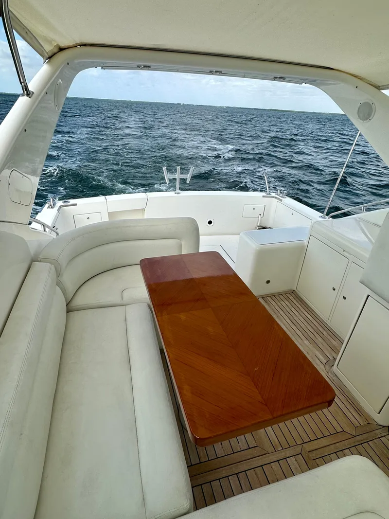 Slide: The Image of 2001 Uniesse 42 Open yacht interior with ocean view, featuring white seating and wooden table. - 49