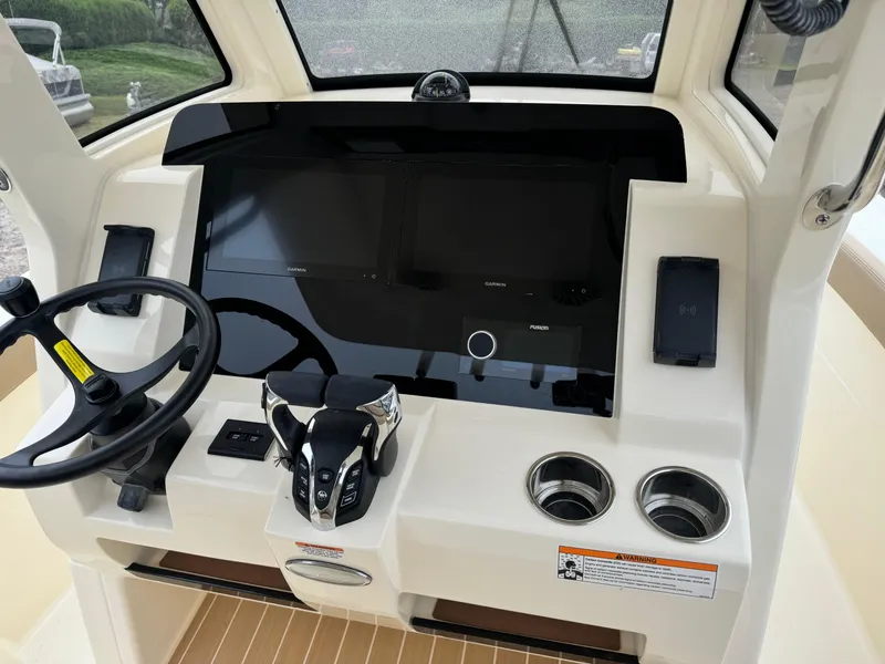 Slide: The Image of 2025 Scout 260 LXF boat dashboard with steering wheel, controls, and cup holders. - 16