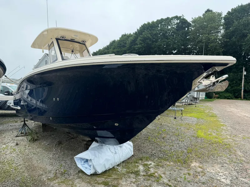 Slide: The Image of 2025 Scout 260 LXF boat on a gravel lot with trees in the background. - 50