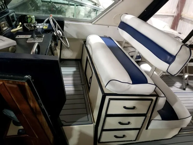 Slide: The Image of 1986 Sea Ray 390 Express helm with white and blue cushioned seating. - 16