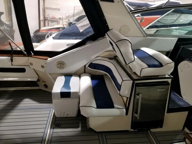 Slide: The Image of 1986 Sea Ray 390 Express interior with cushioned seating and mini fridge. - 2