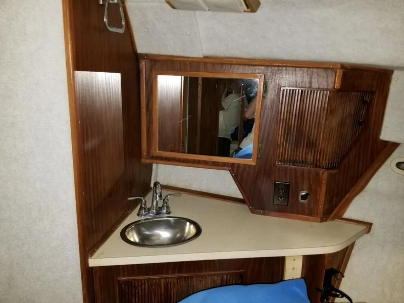Slide: The Image of 1986 Sea Ray 390 Express cabin sink area with mirror and wooden cabinetry. - 4