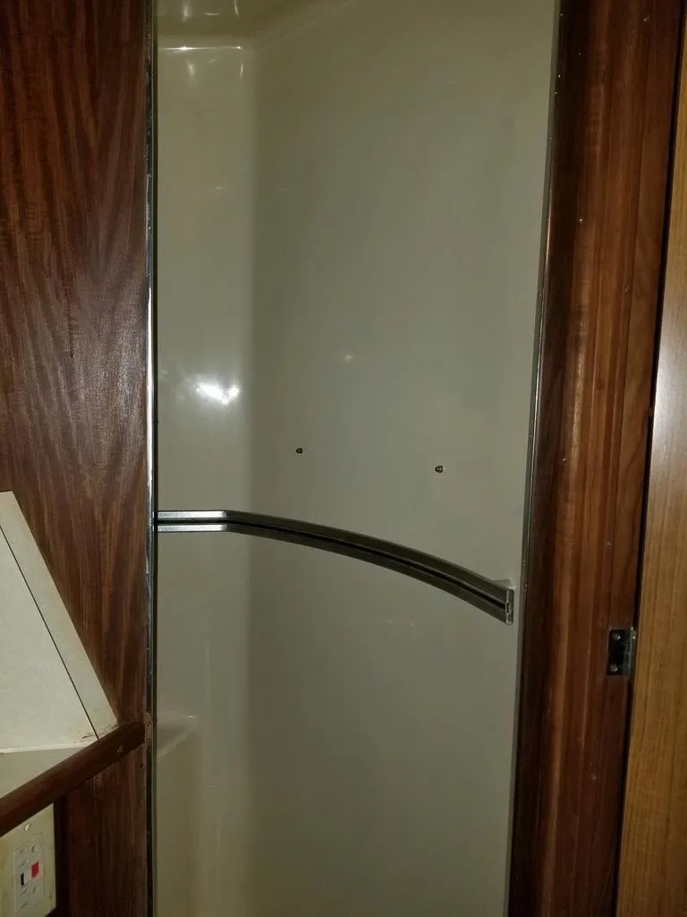 Slide: The Image of 1986 Sea Ray 390 Express shower with wood paneling and curved metal handle. - 8