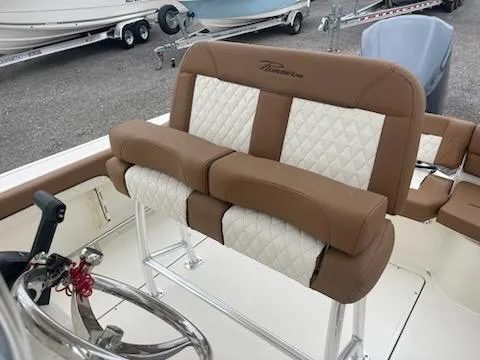 Slide: The Image of 2024 Pioneer 222 Islander boat with tan and white seating, docked near other boats. - 5