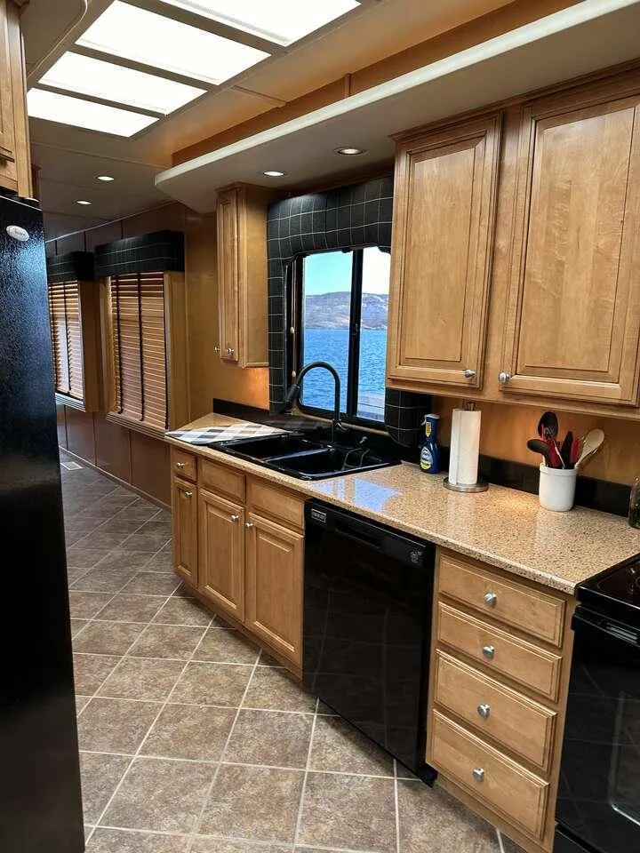 Slide: The Image of Modern kitchen interior in a 2005 Sumerset Top Hat houseboat, featuring wood cabinets and lake view. - 10