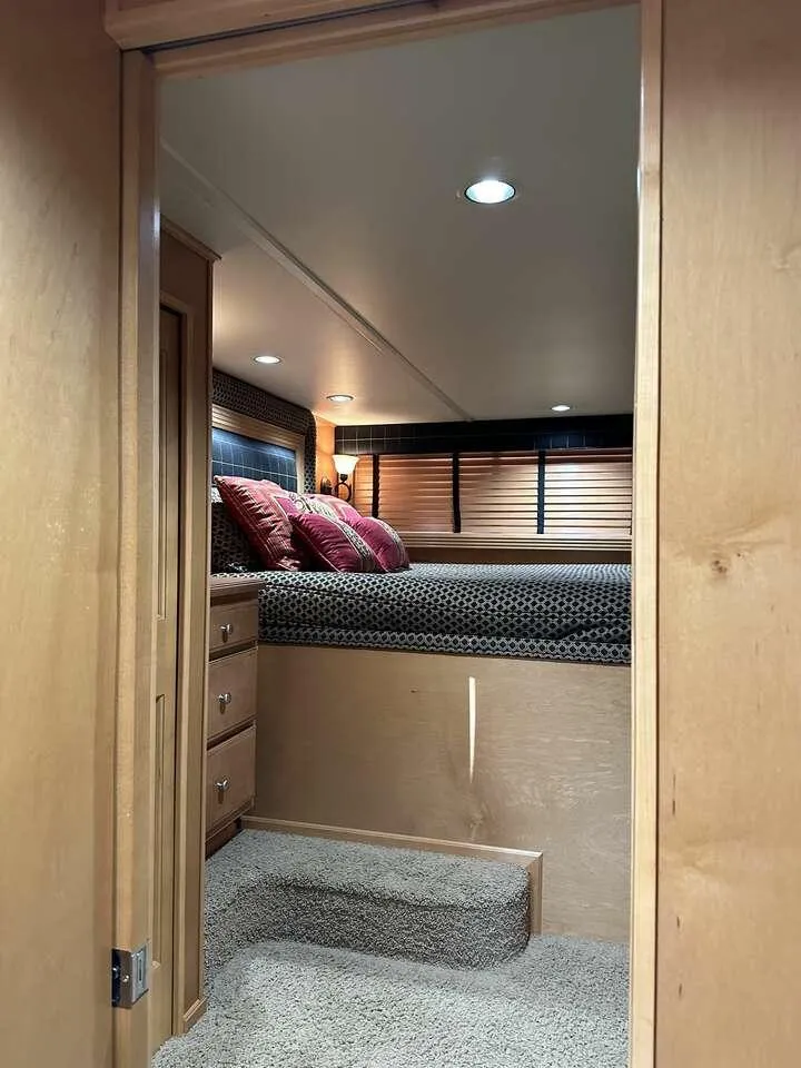 Slide: The Image of Interior of 2005 Sumerset Top Hat, featuring cozy bedroom with carpeted steps and wooden accents. - 12