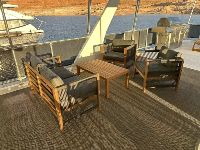 Slide: The Image of Outdoor seating area on a 2005 Sumerset Top Hat houseboat, featuring wooden furniture and a scenic water view. - 25
