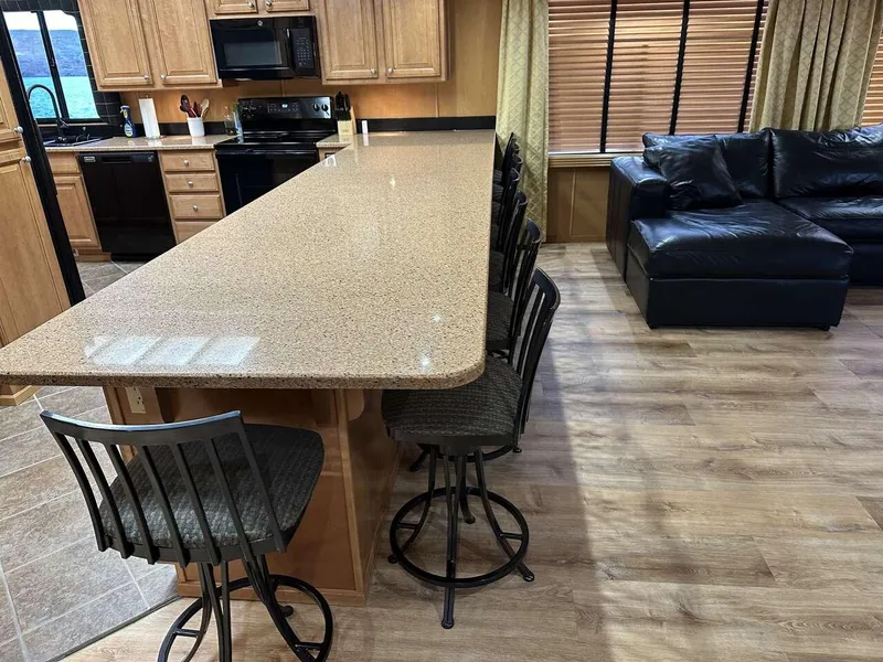 Slide: The Image of Modern kitchen with long countertop, bar stools, and black leather sofa in a 2005 Sumerset model. - 7