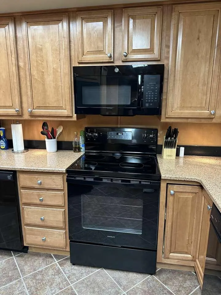 Slide: The Image of Modern kitchen with wooden cabinets, black appliances, and tiled flooring. Sumerset Top Hat 2005 model. - 9