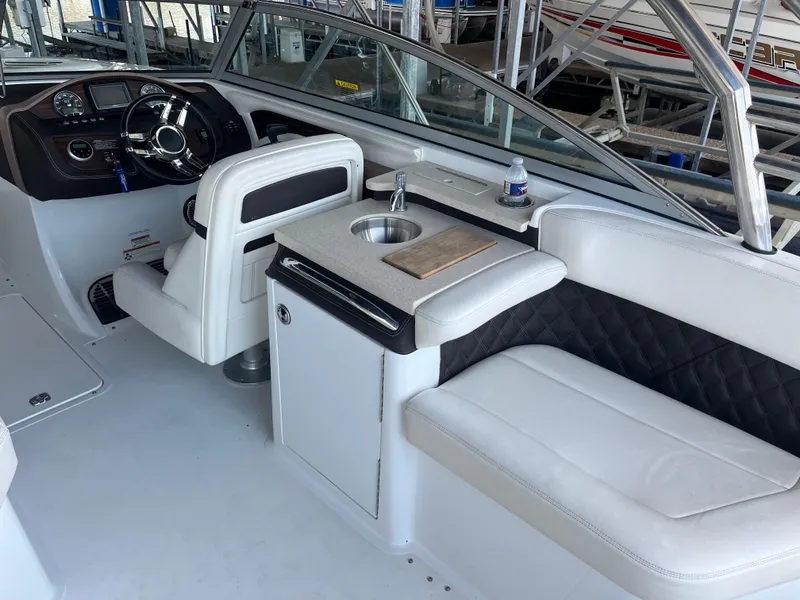 Slide: The Image of 2013 Cobalt A28 boat interior with helm, seating, and mini sink. - 8
