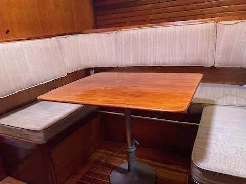 Slide: The Image of 1969 Spencer 44 CC sailboat interior with wooden table and cushioned seating. - 11