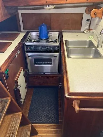 Slide: The Image of 1969 Spencer 44 CC yacht kitchen with stove, sink, and wooden cabinetry. - 17