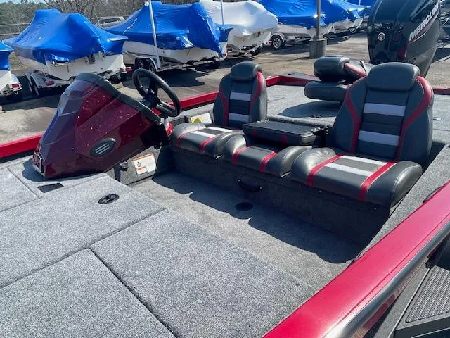Slide: The Image of 2024 Ranger RT188 boat interior with gray and red seating, steering console, and covered boats in background. - 6