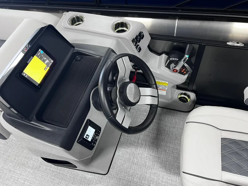 Slide: The Image of 2024 Harris Sunliner 230 boat dashboard with steering wheel and touchscreen display. - 21