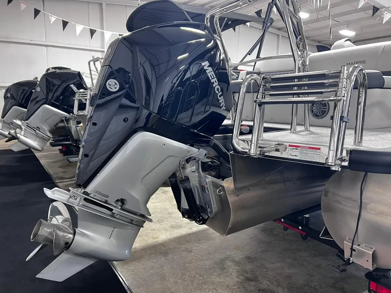 Slide: The Image of 2024 Harris Sunliner 230 pontoon boat with Mercury outboard motor in showroom. - 31
