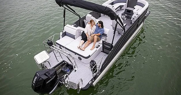 Slide: The Image of 2024 Harris Sunliner 230 pontoon boat on water with two people relaxing. - 9