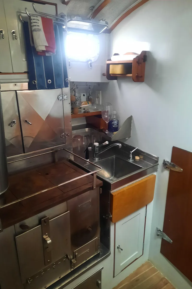 Slide: The Image of Compact kitchen area in a 1947 Rhodes Nevins Picnic Boat, featuring stainless steel sink and storage. - 13