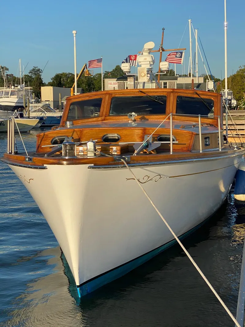 Slide: The Image of 1947 Rhodes Nevins Picnic Boat docked, featuring classic wooden design and American flags. - 2