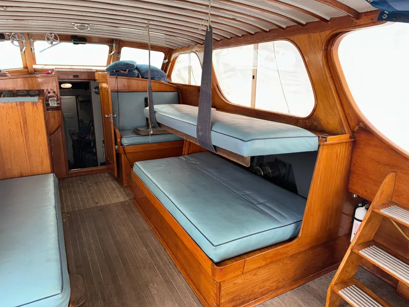 Slide: The Image of 1947 Rhodes Nevins Picnic Boat interior with wooden finish and blue seating. - 4