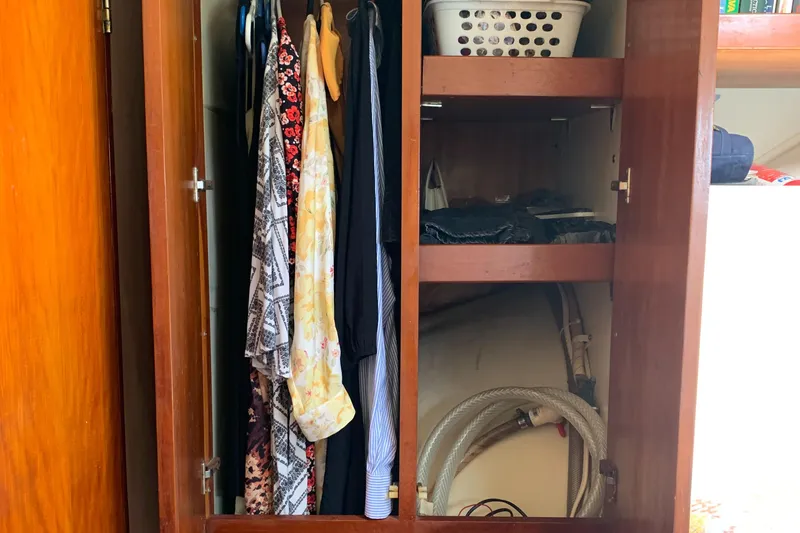 Slide: The Image of Wooden closet with clothes, storage shelves, and laundry basket on Lagoon TPI 42, 1993 model. - 42