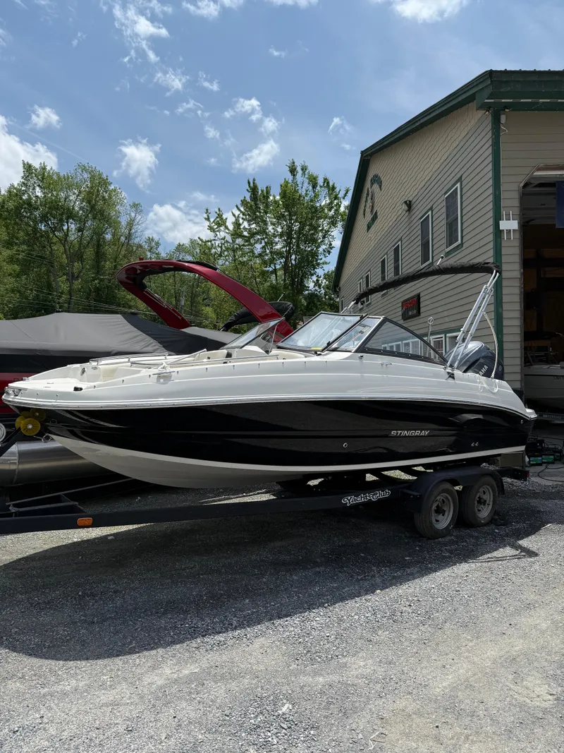The Image of 2024 Stingray 201DC boat on trailer, parked outdoors near a building. - 1