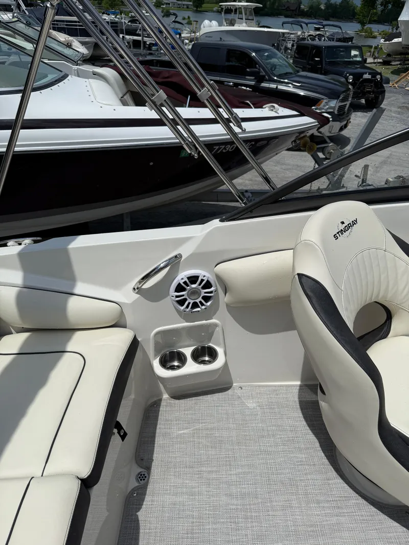 Slide: The Image of 2024 Stingray 201DC boat interior with white seating, cup holders, and speaker. - 16