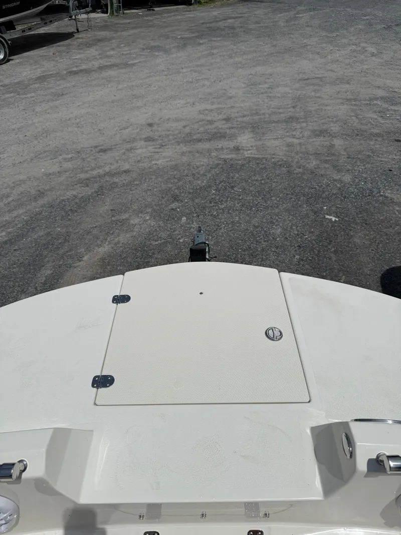 Slide: The Image of 2024 Stingray 201DC boat deck on gravel surface, showcasing hatch and hardware. - 23