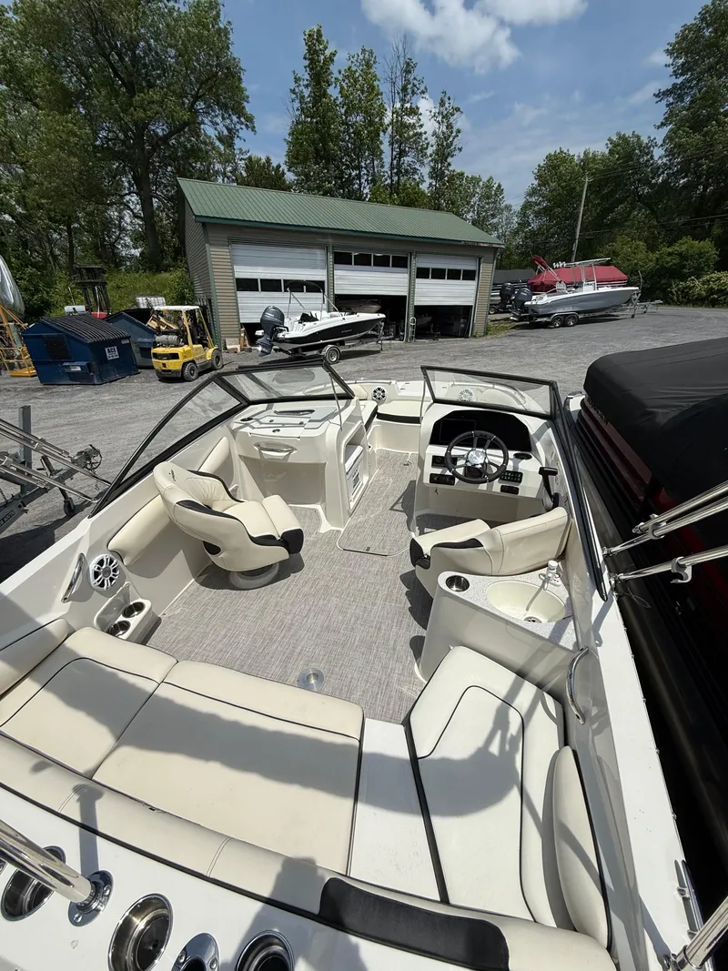 Slide: The Image of 2024 Stingray 201DC boat interior with seating, steering wheel, and dashboard in a marina setting. - 28