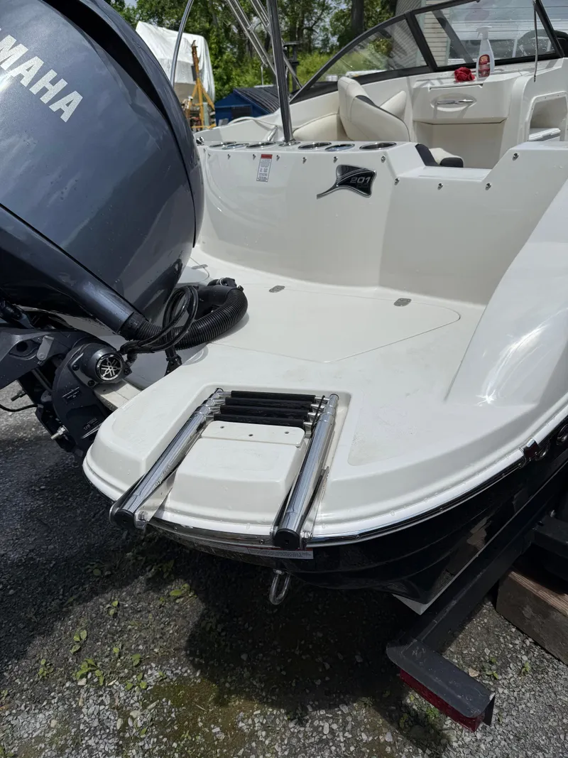 Slide: The Image of 2024 Stingray 201DC boat with Yamaha engine and swim ladder, parked outdoors. - 3
