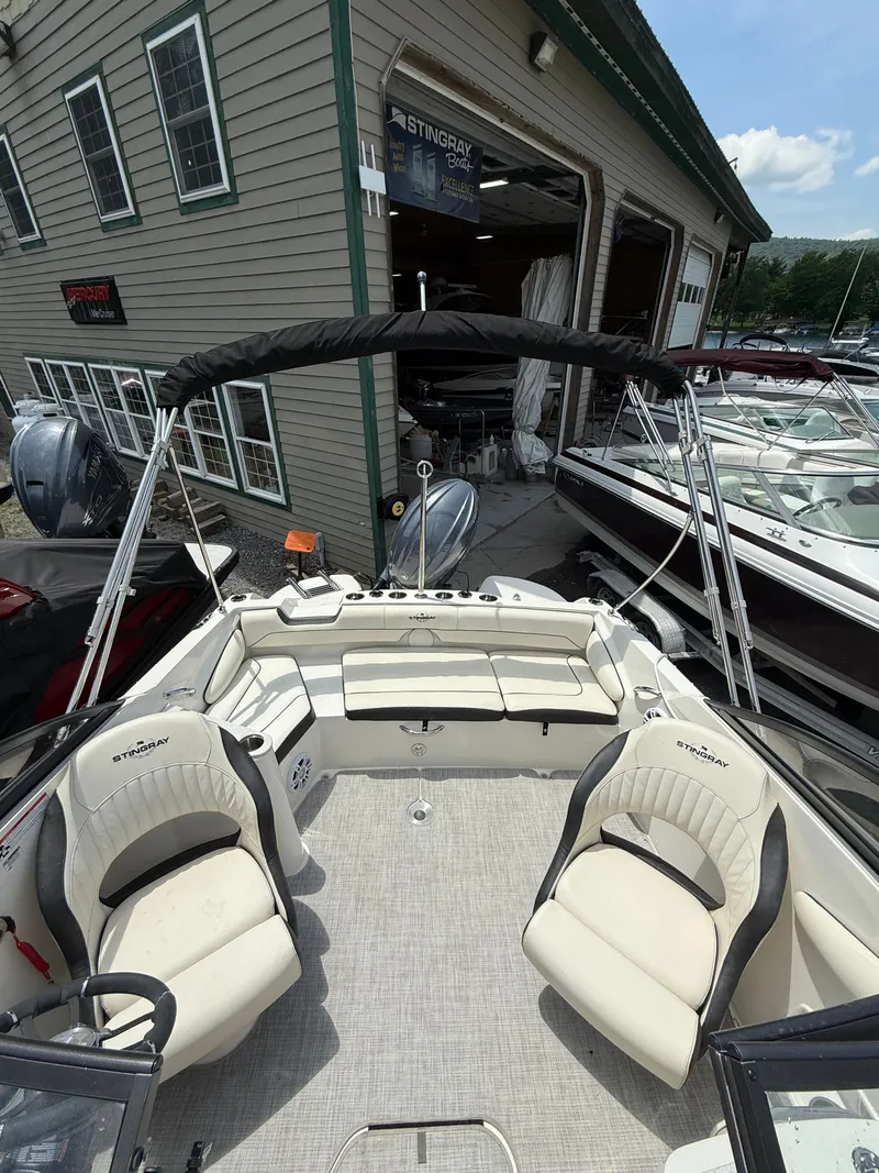 Slide: The Image of 2024 Stingray 201DC boat interior with seating, docked near a showroom. - 8