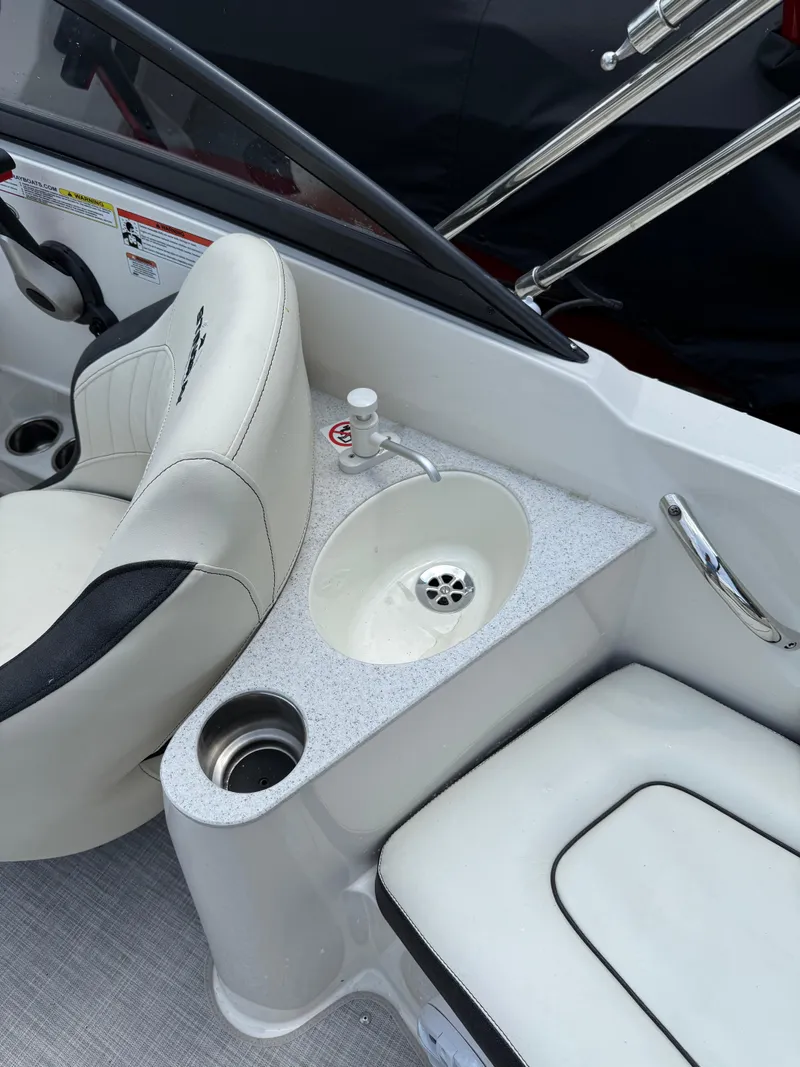 Slide: The Image of 2024 Stingray 201DC boat interior with white seating, sink, and cup holder. - 9