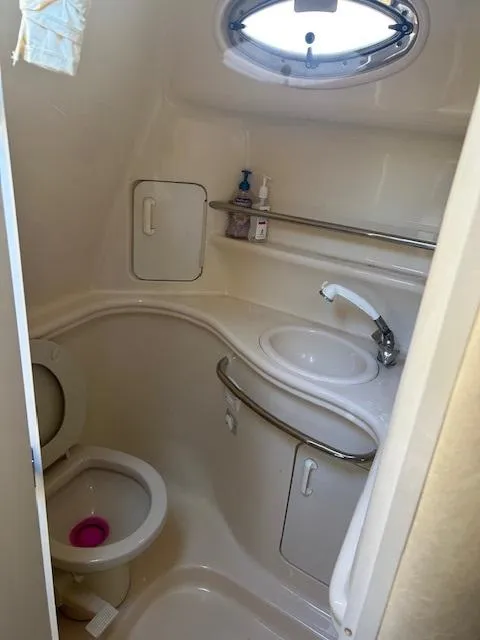 Slide: The Image of Compact bathroom in 2001 Sea Ray 340 Sundancer boat with sink, toilet, and porthole window. - 14