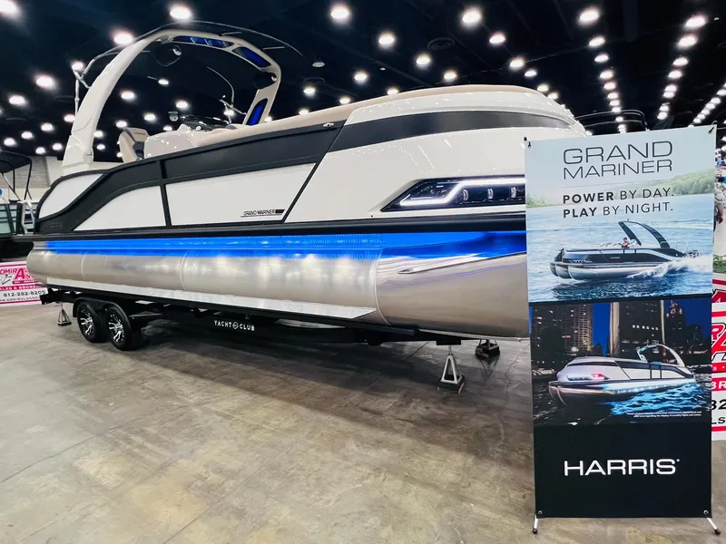 The Image of 2024 Harris 250 Grand Mariner V10 400 boat displayed indoors with promotional banner. - 0
