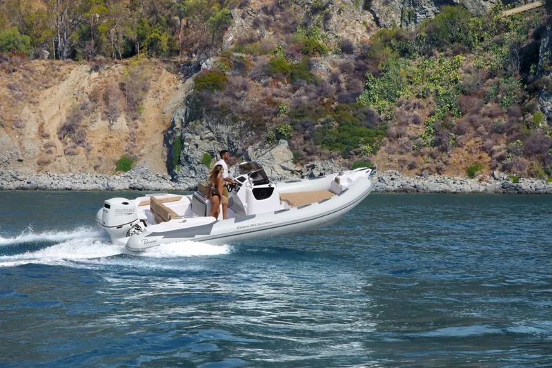 Slide: The Image of 2025 Ranieri Cayman 23.0 Sport Touring boat cruising near rocky coastline. - 16