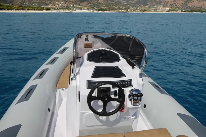 Slide: The Image of 2025 Ranieri Cayman 23.0 Sport Touring boat on open water, featuring modern console and steering. - 18