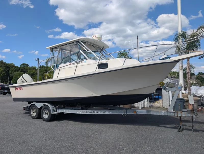 Slide: The Image of 1999 Parker 2510 Walkaround boat on a trailer under a partly cloudy sky. - 2