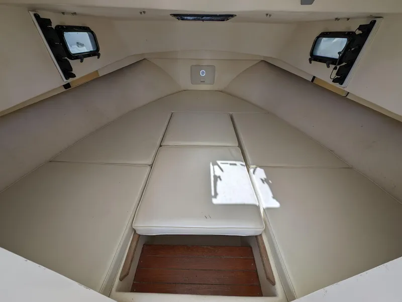 Slide: The Image of 1999 Parker 2510 Walkaround boat cabin interior with cushioned seating and portholes. - 27