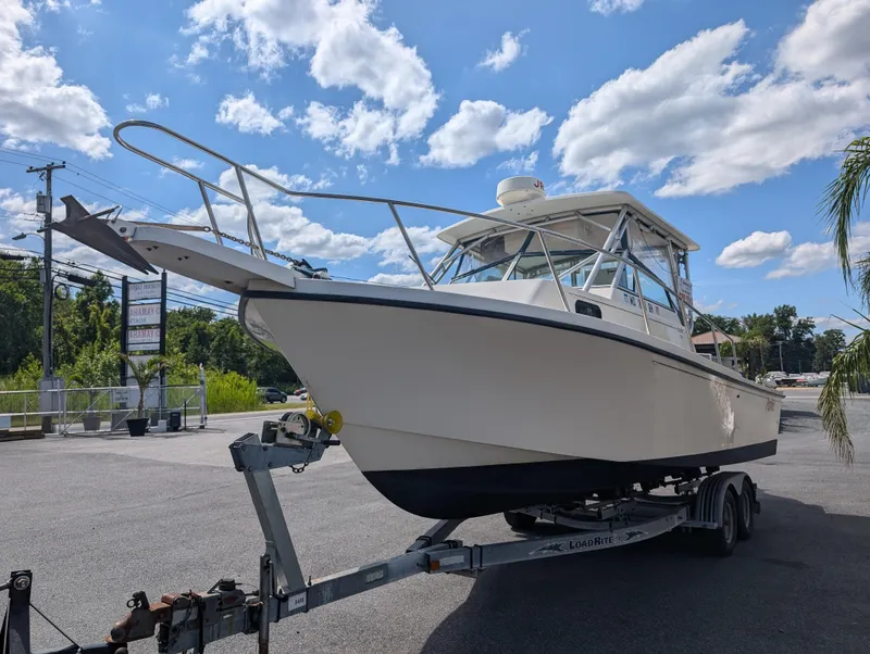 Slide: The Image of 1999 Parker 2510 Walkaround boat on a trailer under a blue sky with clouds. - 4