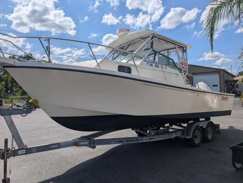 Slide: The Image of 1999 Parker 2510 Walkaround boat on a trailer under a sunny sky. - 5
