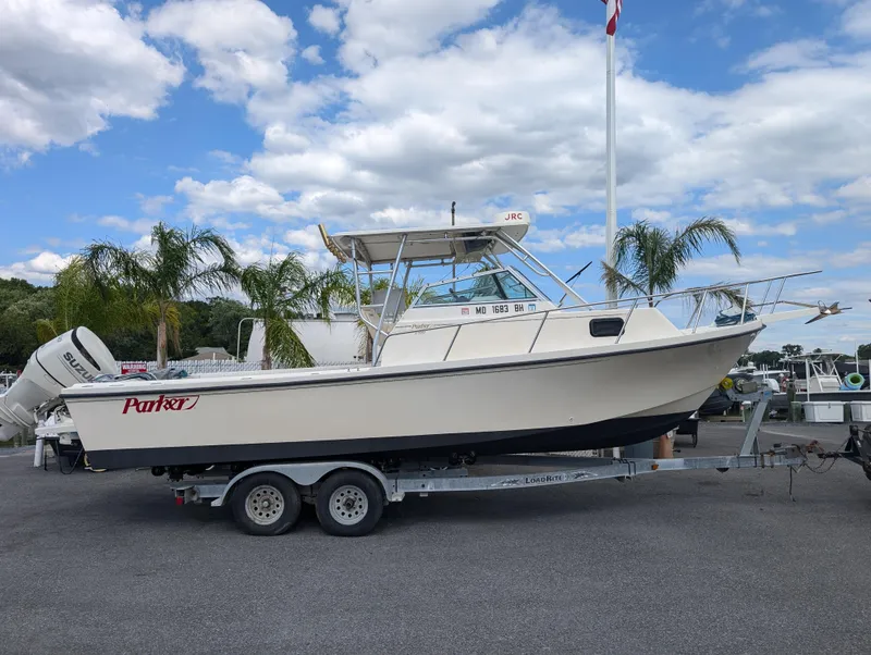 Slide: The Image of 1999 Parker 2510 Walkaround boat on a trailer under a partly cloudy sky. - 9