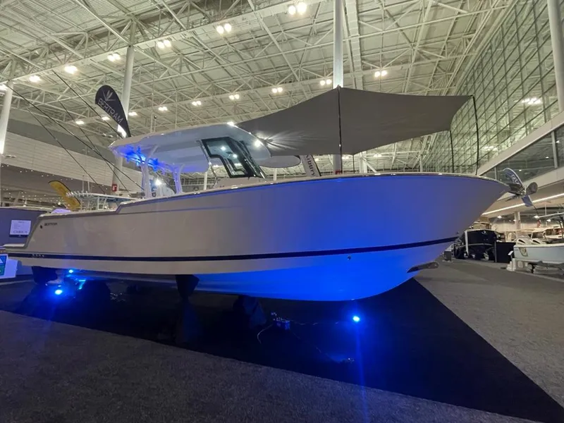 Slide: The Image of 2023 Bertram 28 CC boat displayed at an indoor boat show with blue accent lighting. - 8