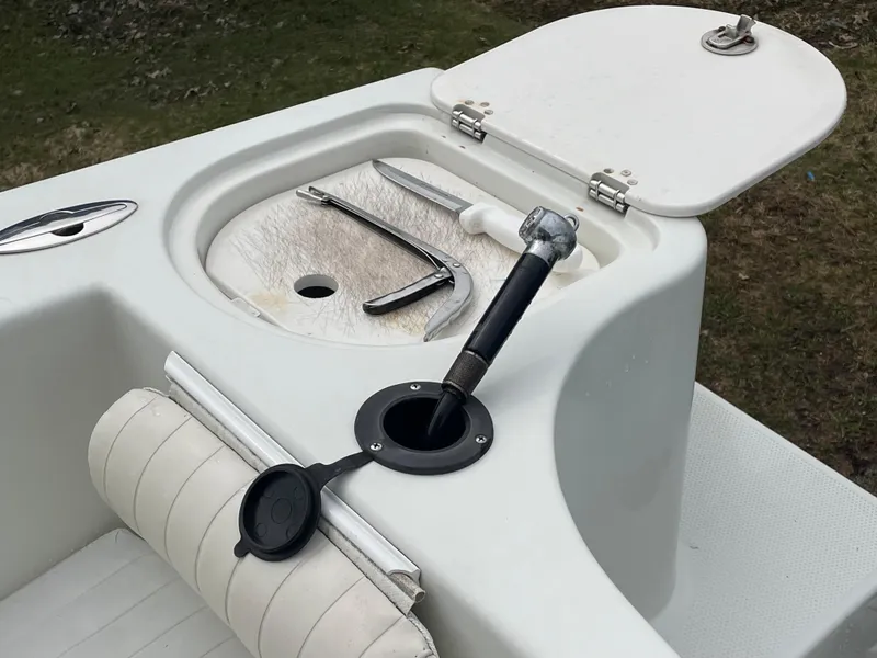Slide: The Image of 2006 Sailfish 2360 CC boat with open storage compartment and fishing tools. - 21